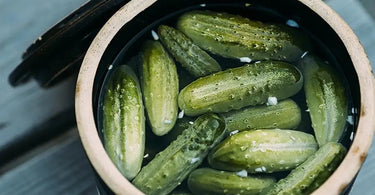 Garden cucumbers being pickled with salt in a brine container