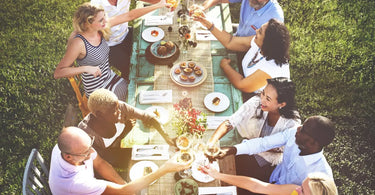 Group of friends having a garden party dinner on a long table