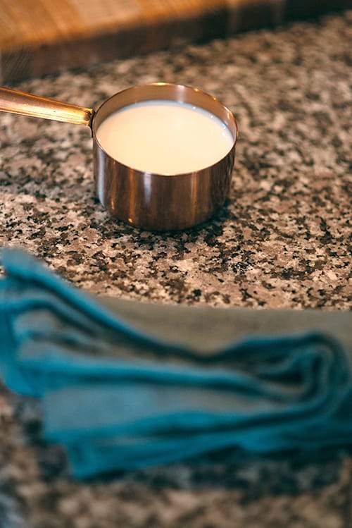 milk in measuring cup on counter top with towel
