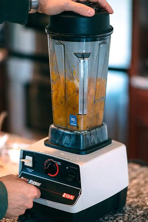 blender with pumpkin puree and hand pressing button