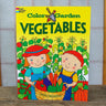 Color and Garden Vegetables children's coloring book with bright yellow illustrated cover, sitting on wooden table.