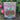 Box of Down to Earth All Natural Fertilizer Rose & Flower Mix in a garden with pink flowers.