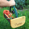 Gardener holding a Maine Garden hod filled with plants and vegetables, with 'Pinetree Garden Seeds' logo.